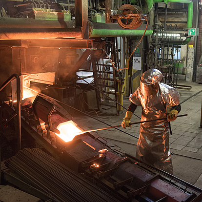 Foto: Aurubis: Aribeiter*in mit langem Metallstab in der Hand